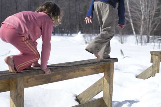 kids walking on railing in snow